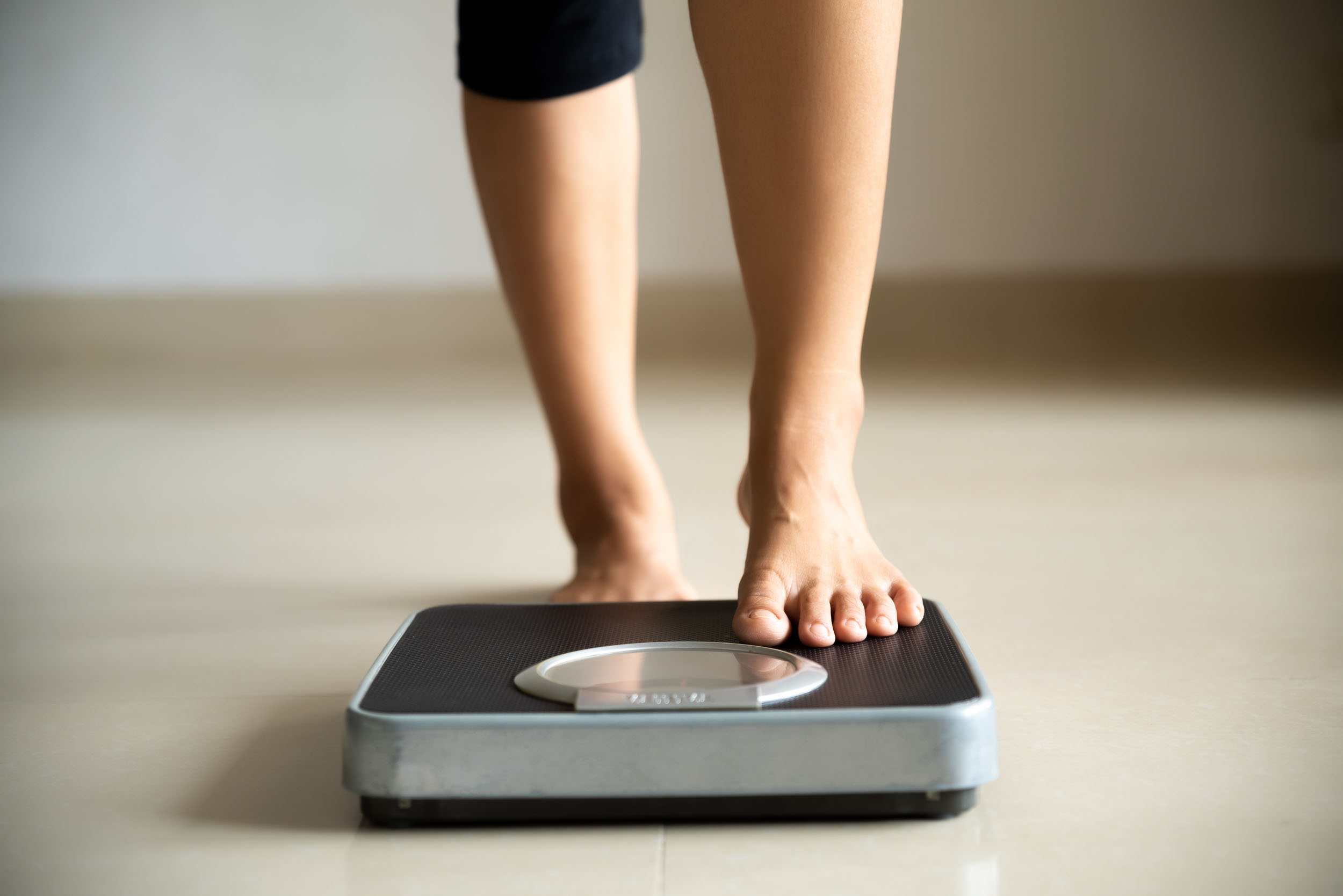 Female leg stepping on weigh scales representing our weight loss program